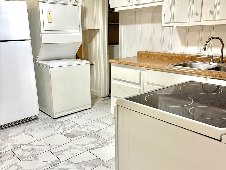 Another view of the kitchen: Fridge + freezer, microwave, stove+oven, and washer+ dryer included. Updated flooring and plenty of storage on walls and pantry.