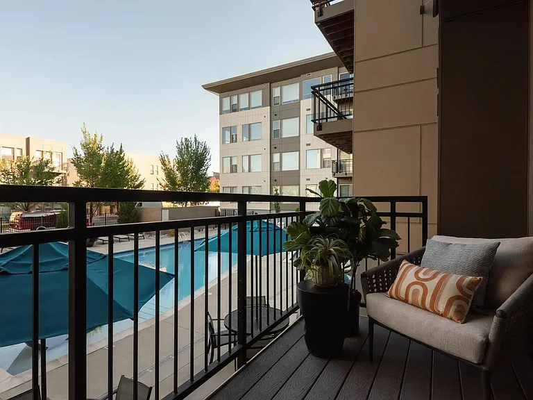 Cozy Balcony with Outdoor Seating and Views of Poolside Umbrellas
