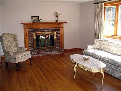 Living room with fireplace, bay window, and hardwood floors. 