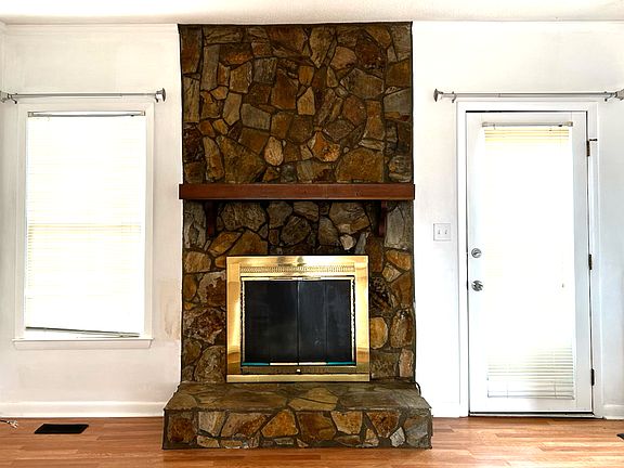 The classic stone-faced fireplace highlights the newly installed hardwood floors and beautiful earthtone of the living room.