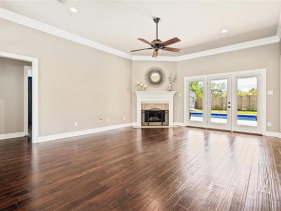 Unfurnished living room with ornamental molding, a fireplace, ceiling fan, and dark wood-type flooring