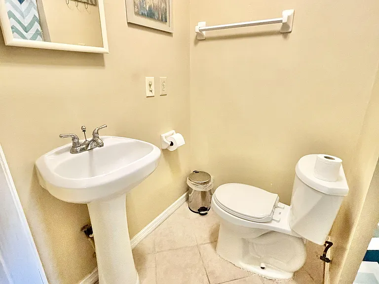 full bath with pedestal sink, framed mirror, and towel bar.