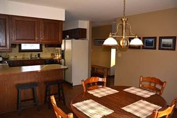 A great view of the warm and inviting kitchen and dining areas.  Notice the eat-in kitchen with a large breakfast bar.  All kitchen appliances stay with the home. The opening in the center of the image leads directly into the living area providing fantastic flow.