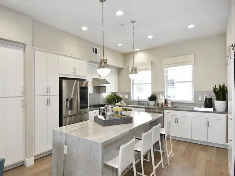 Open floorplan chefs kitchen with quartz countertops and white cabinetry