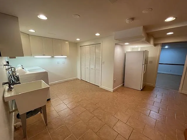 Basement Laundry Room with brand new washer and dryer, spacious storage in wall cabinets, additional storage closet, and bonus full-size refrigerator with freezer.