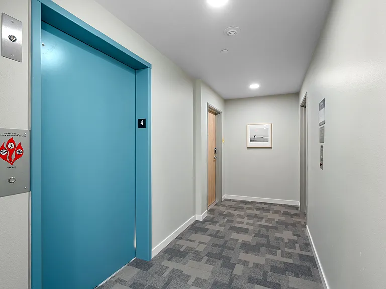 This modern hallway features a sleek design with a striking blue door, adding a pop of color to the space.