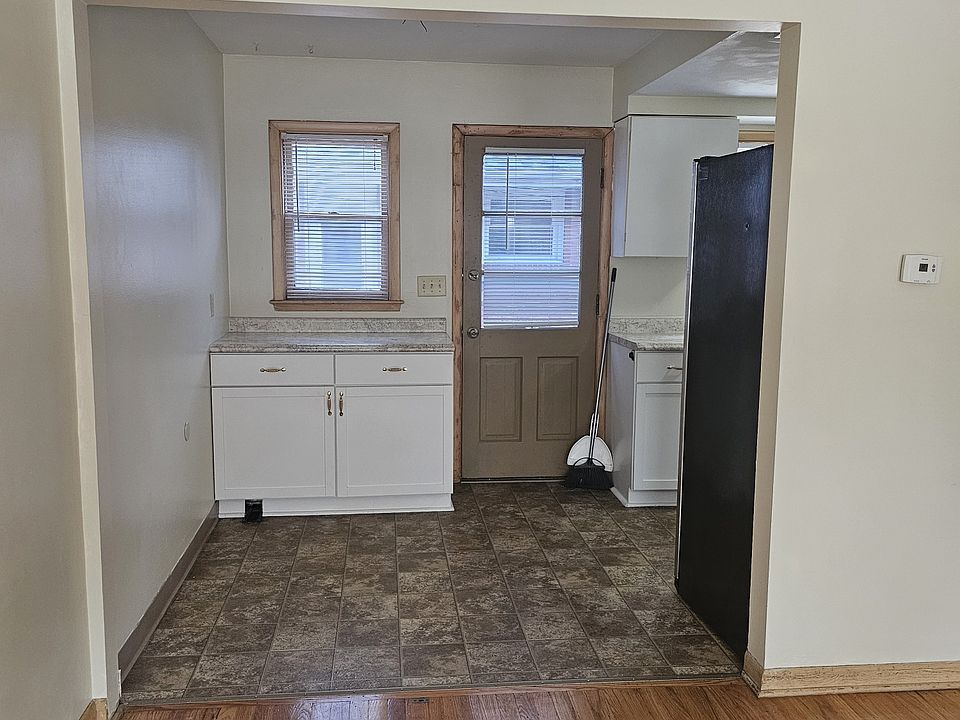 View from front door of back door and extra cabinet on kitchen entryway. Back door opens to cement steps and area for grilling.