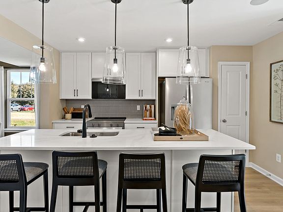 Enjoy cooking and gathering around the kitchen island with bar seating and modern lighting.