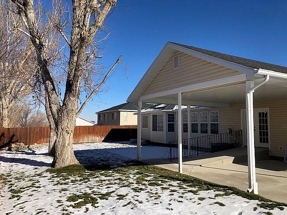 Rear yard with mature shade trees and lawn. Lit patio with shade awning for afternoon sun