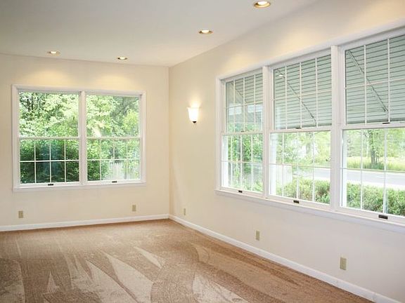 Large sun-filled living room features new carpet, fresh paint, updated lighting, and lots of windows!