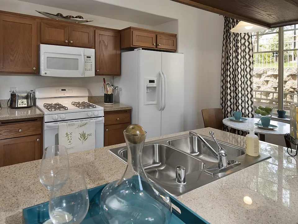 Classic Package I kitchen with maple cabinetry, beige speckled granite countertops, white appliances, and tile flooring