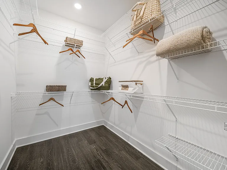 Spacious walk-in closet with sleek wire shelving, wooden hangers, and stylish storage baskets, offering ample organization space.