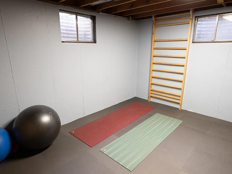 Exercise room with Swedish ladder, gym flooring, and north and west facing windows in window wells.