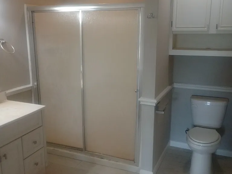 Guest bathroom (main bathroom) located off the hallway completely remodeled with tile flooring, single vanity, walk-in shower, and cabinets.