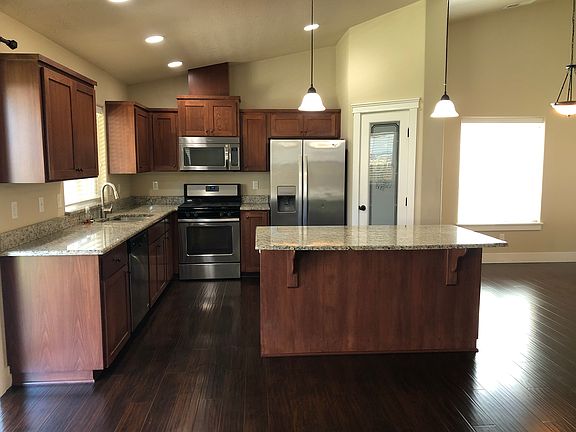 Kitchen with granite counters, SS appliances, including refrigerator, and center island with bar seating.