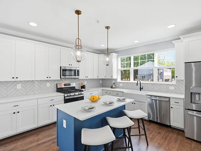 Chef's kitchen with island, farmhouse sink, herringbone backsplash, gas range, and breakfast nook.