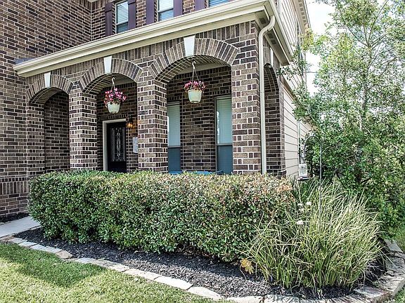 Neatly manicured hedges and mature landscaping surround the pretty front porch...