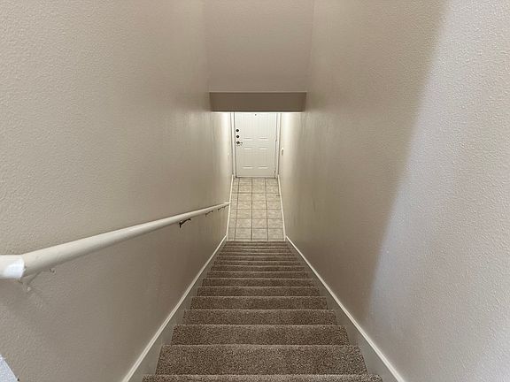 Inviting staircase with plush carpeting leading to a stylish entryway, featuring elegant tiled flooring and a welcoming front door. Inviting staircase with plush carpeting leading to a stylish entryway, featuring elegant tiled flooring and a welcoming fro