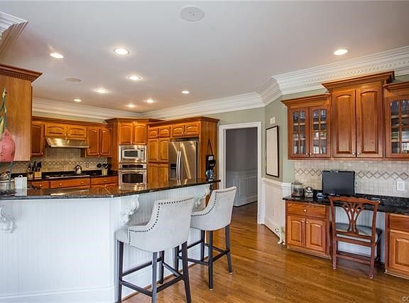 Amazing Granite Kitchen w/ SS, Hardwood Floors, Breakfast bar, and desk area with tile backsplash.