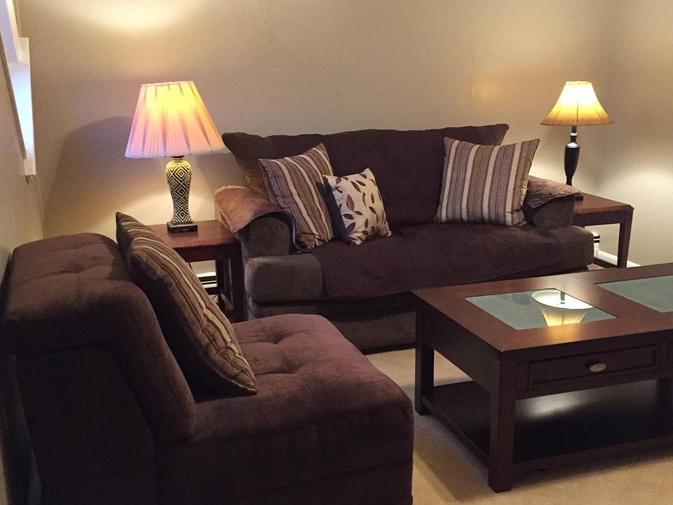 Livingroom with large walk-in closet, sofa, two chairs, TV , area rug ,coffee table ,side tables and lamps
