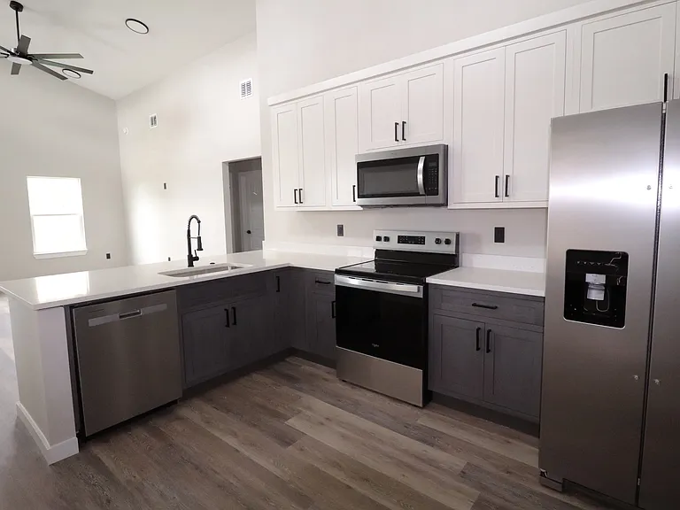 Modern kitchen featuring new stainless steel appliances, white cabinetry, and clean contemporary finishes. Functional layout with plenty of storage.
