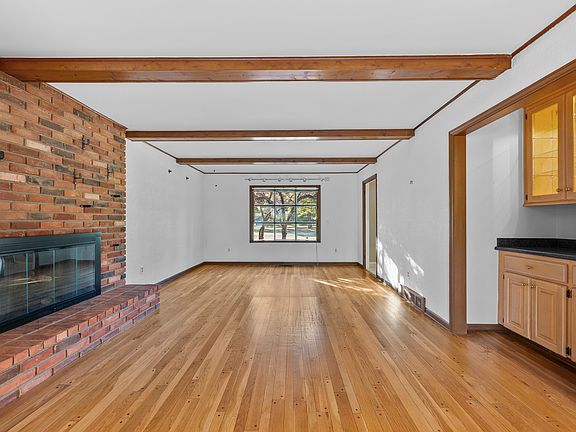 Cozy family room with brick fireplace, wood-beamed ceiling, and built-in wet bar.