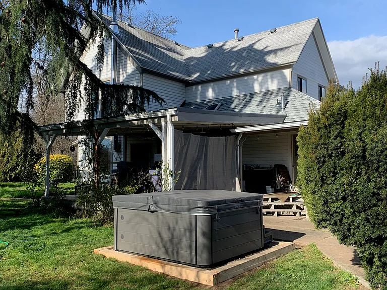 Hot tub surrounded by fenced in yard, filled with flower and fruit gardens