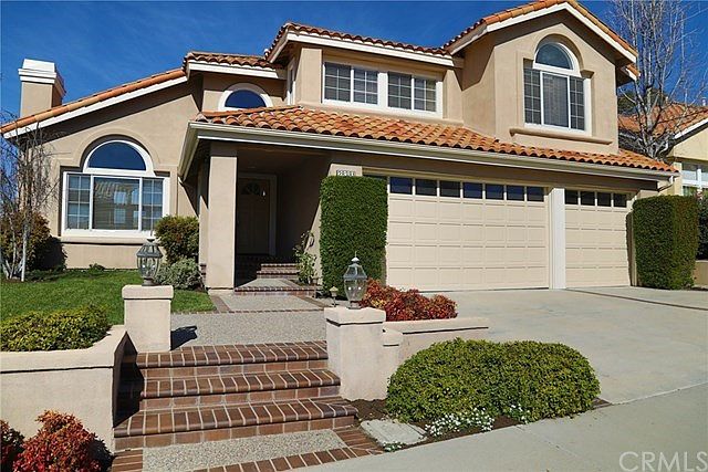 Front of home showing three car garage, custom hard scape and land scape as well as a large driveway