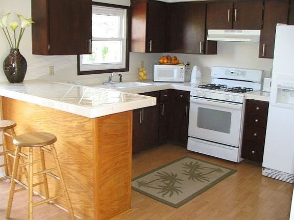 kitchen is clean and bright with tiled countertops and hardwood floors