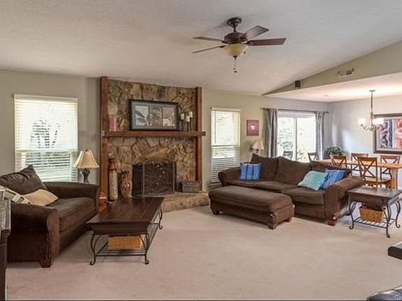 Large greatroom with vaulted ceilings, fan and stone firepla