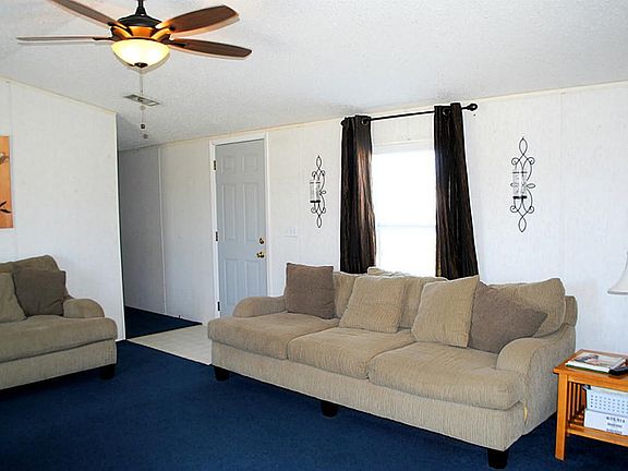 Living room has ceiling fan/light fixture, 2 inch window blinds, curtains & view of front yard.