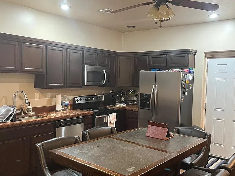 Functional eat-in kitchen with ample dark cabinetry, stainless appliances, and a dedicated dining table for everyday meals.