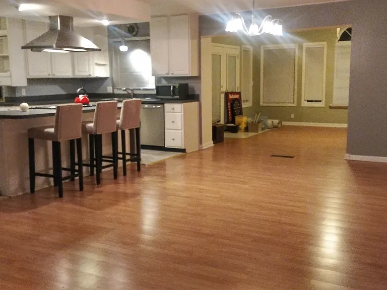 Open-concept floor plan with a kitchen island, dining area with outdoor views, and an expanded living room configured into two functional living spaces.