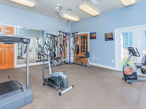 Modern gym with exercise machines and large windows for natural light at Crescent Village in Elgin, TX.