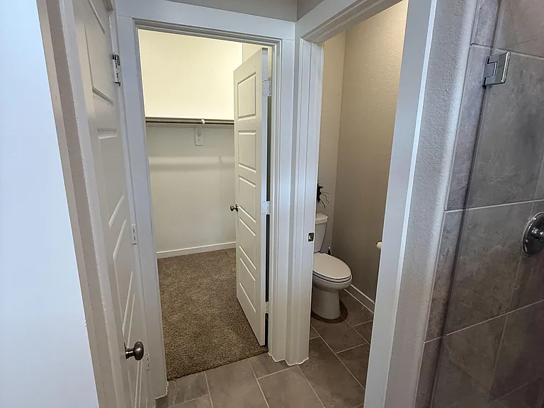 Bathroom area with tiled flooring, walk-in closet access, and a shower/tub surround for easy daily routines.