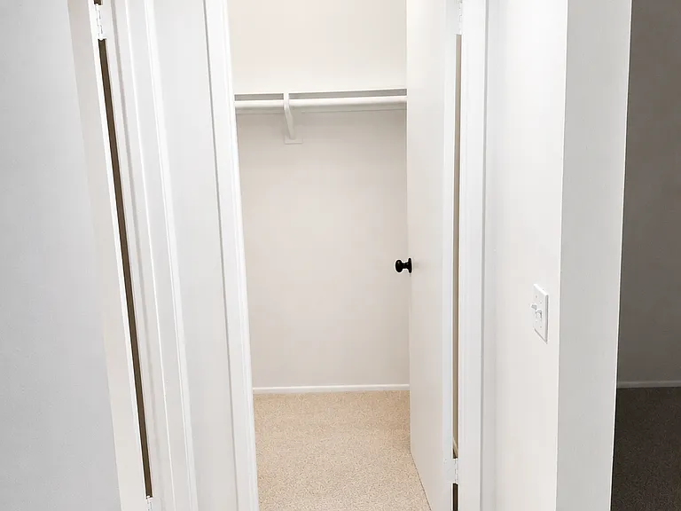 Walk-in master bedroom closet with built-in shelving and hanging space for convenient storage.