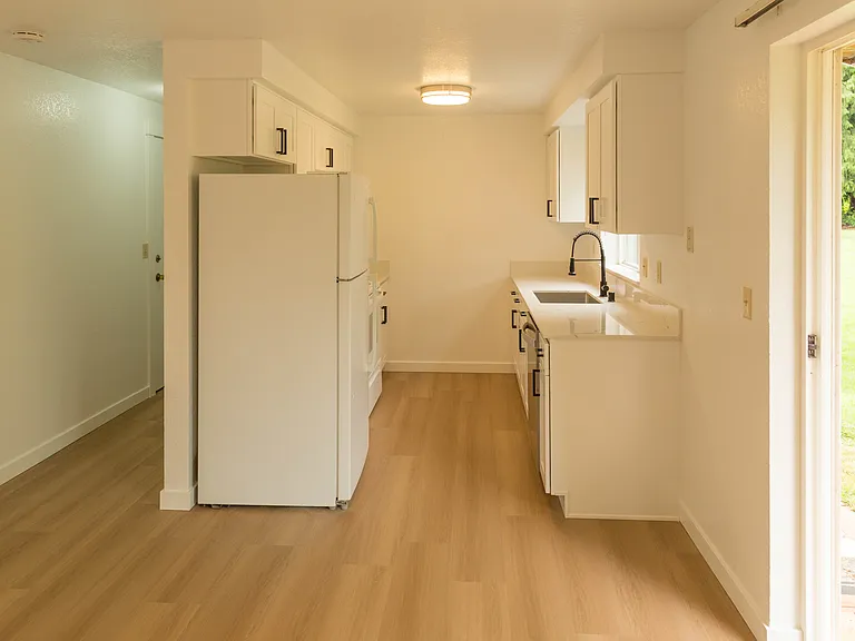 Bright galley-style kitchen with brand-new cabinetry, updated flooring, modern finishes, and direct access to the private backyard deck for indoor-outdoor living.