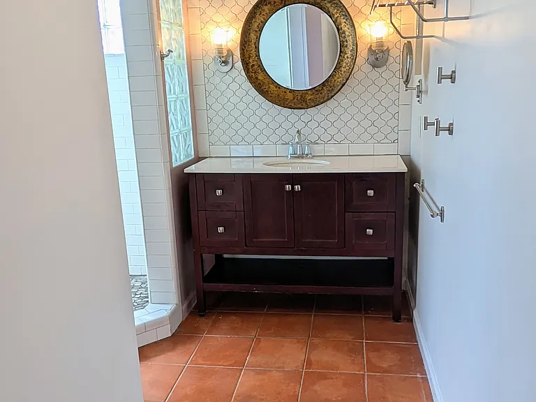 Walkway into the bathroom with Italian tile flooring and ample open shelving.