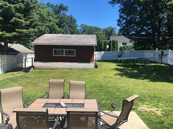 Fenced in Backyard with Patio Set, Shed with Hot Tub, and Trampoline.
