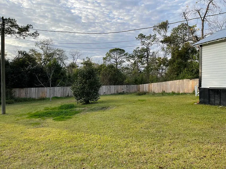 back and side view of the attached vacant lot with fence