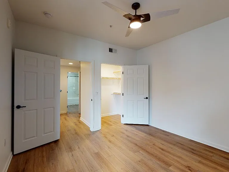 Spacious apartment bedroom with large closet and wood-style flooring.