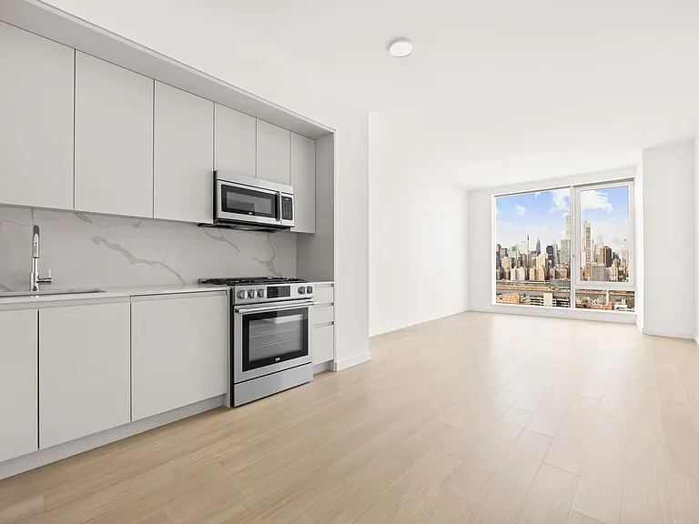 Elevate your lifestyle at Aura with this stylish open-concept kitchen featuring modern appliances and stunning city views. Bright, spacious, and designed for comfort, it's the perfect backdrop for your urban living. Schedule a visit today!