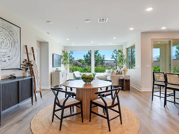 A modern and spacious dining area with a round wooden table and black bar stools, surrounded by larg