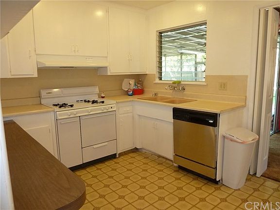 Original kitchen cabinets with newer stove and dishwasher.