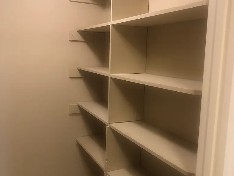 Floor to ceiling shelving in laundry room across from washer and dryer.