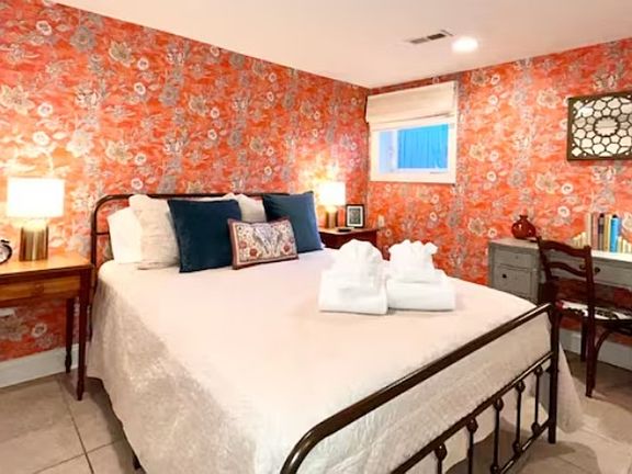 Furnished bedroom with queen bed, side tables, desk