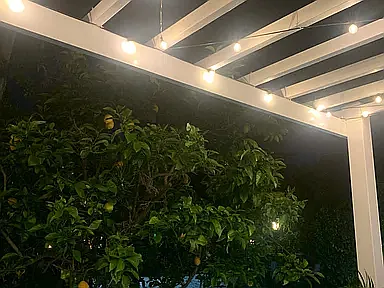 Backyard trellis over porch with lights and shade panels