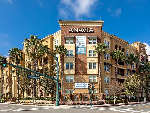 Exterior of apartment building lined with palm trees.