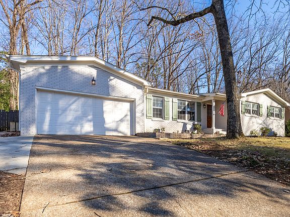 Long driveway with additional paved parking to left of 2 car garage