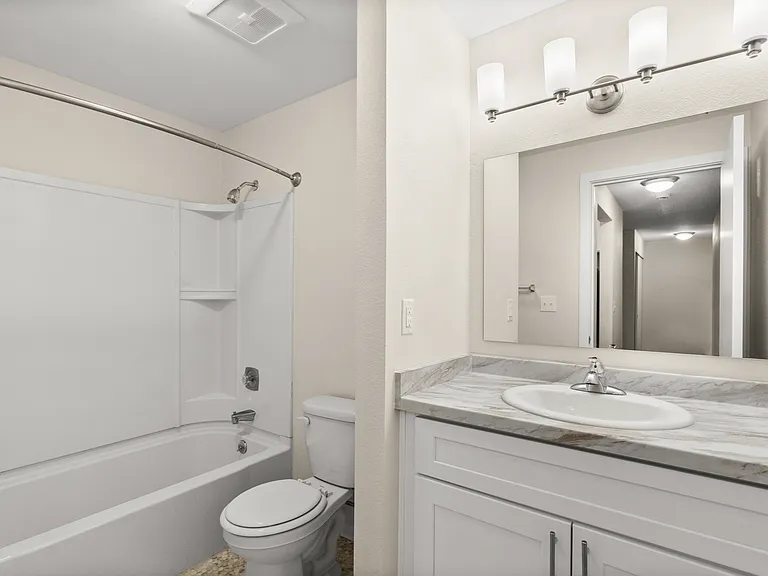 Elegant bathroom with marble-style vanity and full bathtub.